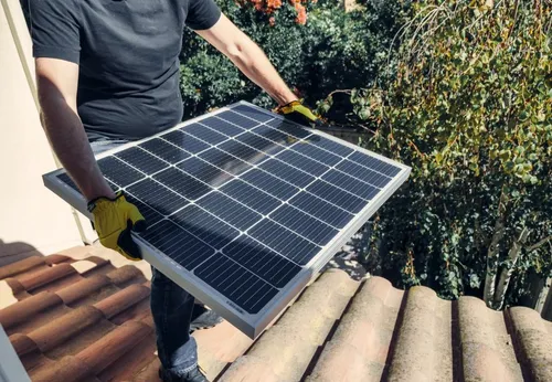 Worker positioning a solar panel on a residential roof