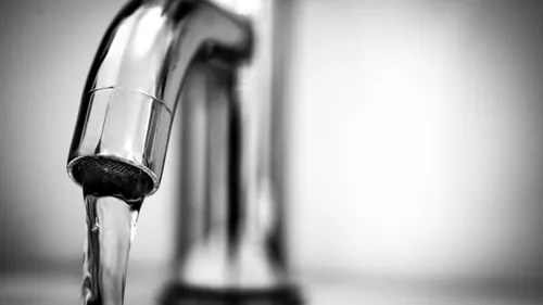 A close-up shows clear water running from a stainless-steel faucet.