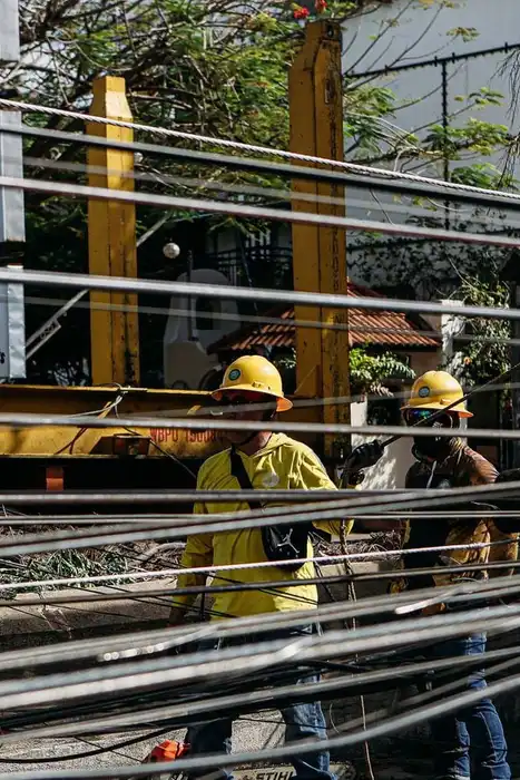 Utility workers in hard hats repairing tangled power lines outdoors.