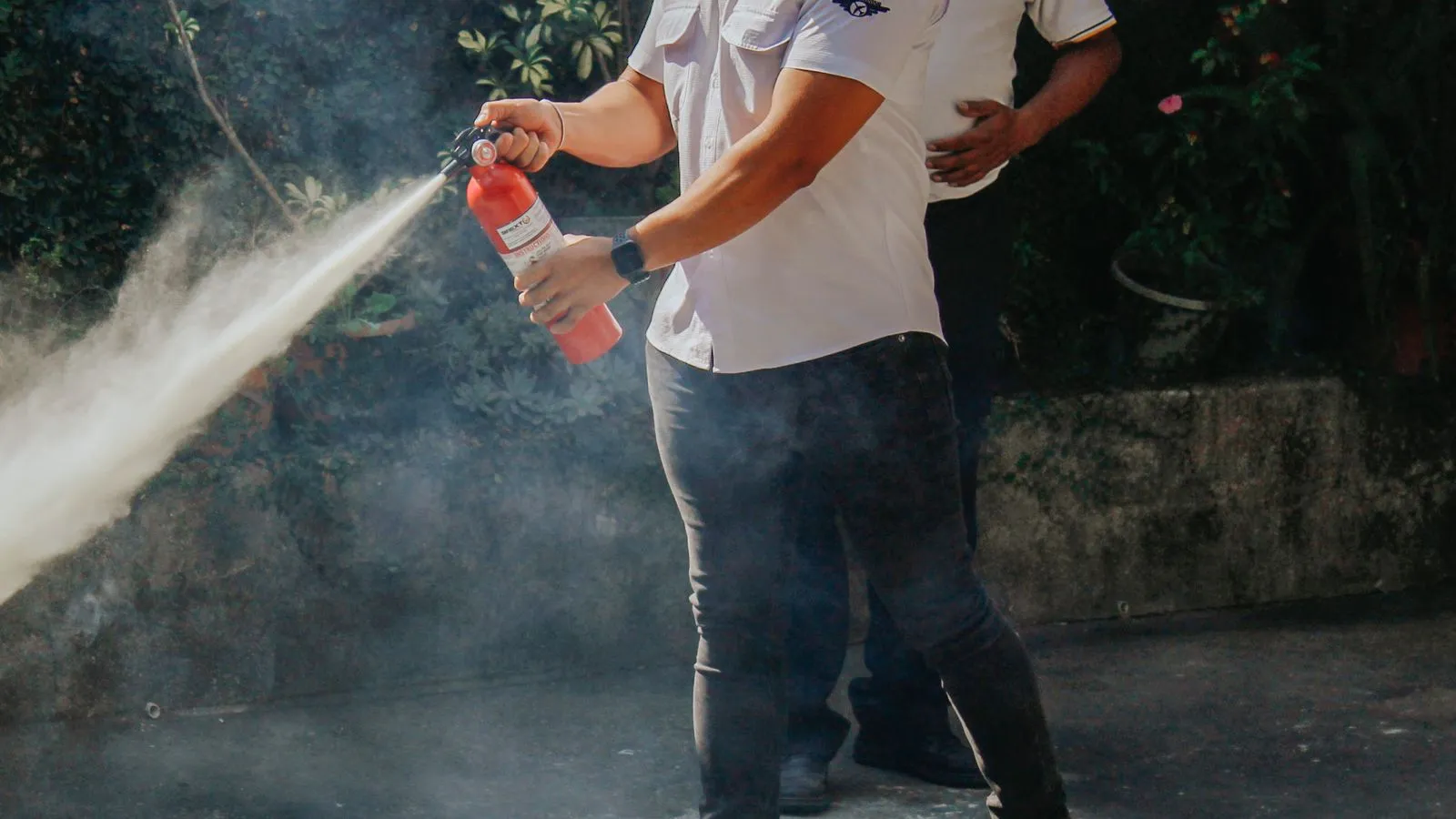 Two men demonstrate a fire extinguisher outdoors