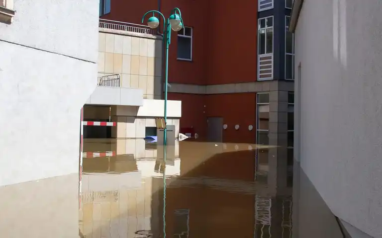 Floodwater standing between residential buildings on an urban street