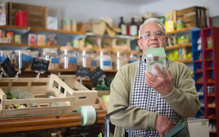 Older shopper looking at a packaged grocery product.