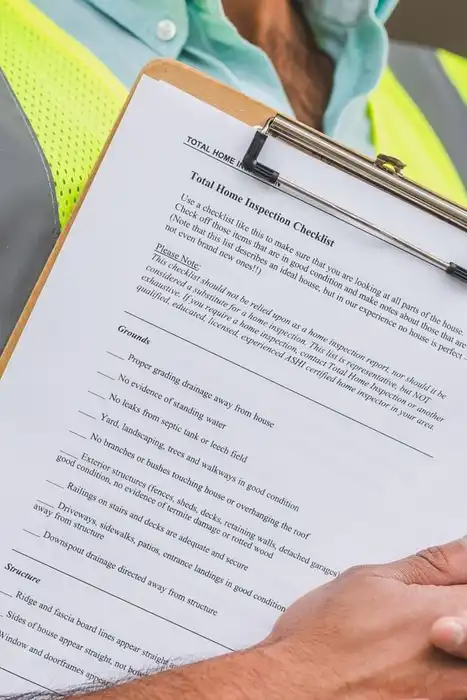 A home inspector in a reflective vest reviewing a checklist.