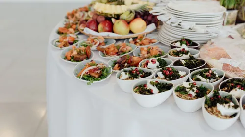 Small dishes of prepared food and fruit are arranged on a buffet table.
