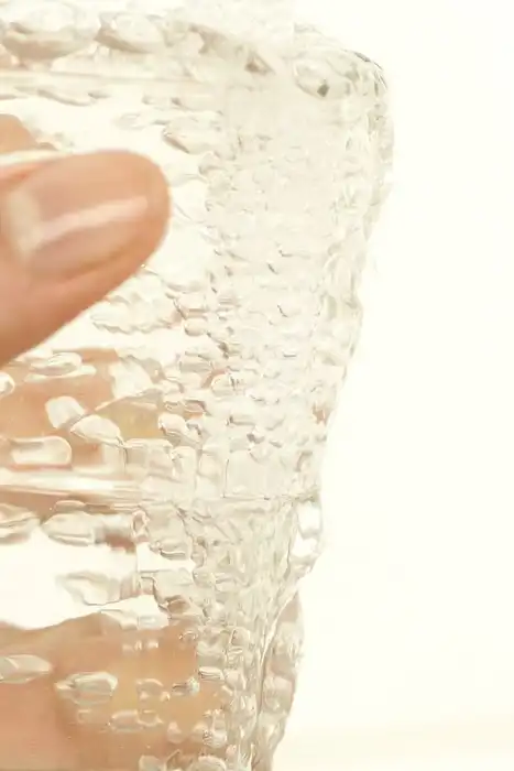 Hand holding a glass filled with water.