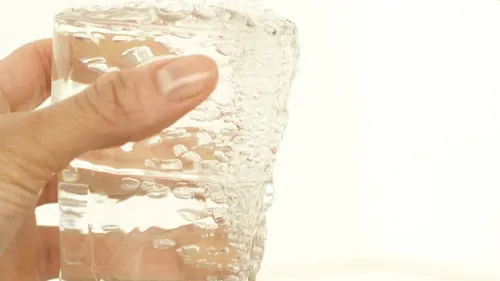 Hand holding a glass filled with water.