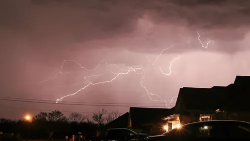 Lightning flashes over a residential neighborhood at night.