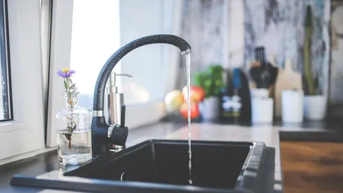A kitchen faucet sends a stream of water into a sink.