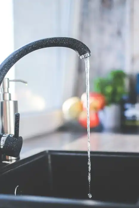 A kitchen faucet sends a stream of water into a sink.