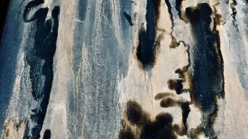 Dark mildew stains and mottled discoloration on a weathered wall surface.