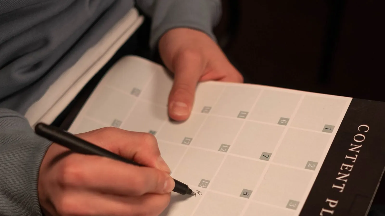 A person writing notes in an open planner.