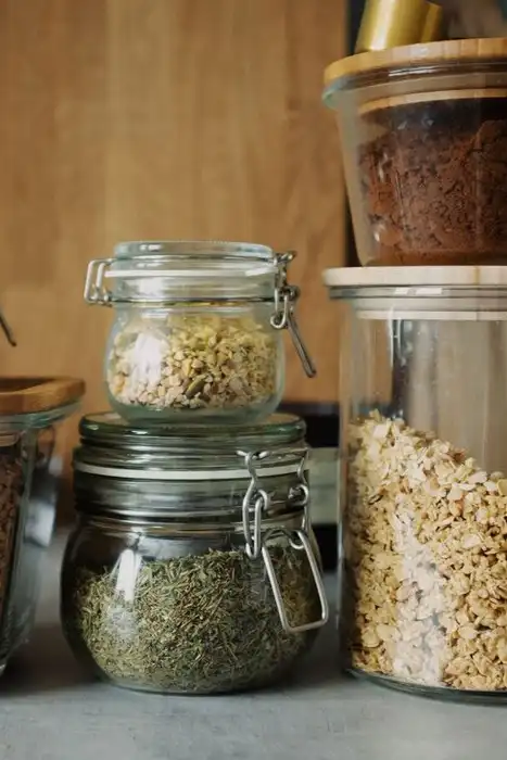 Glass jars of grains, dry goods, and cookies line a pantry counter.