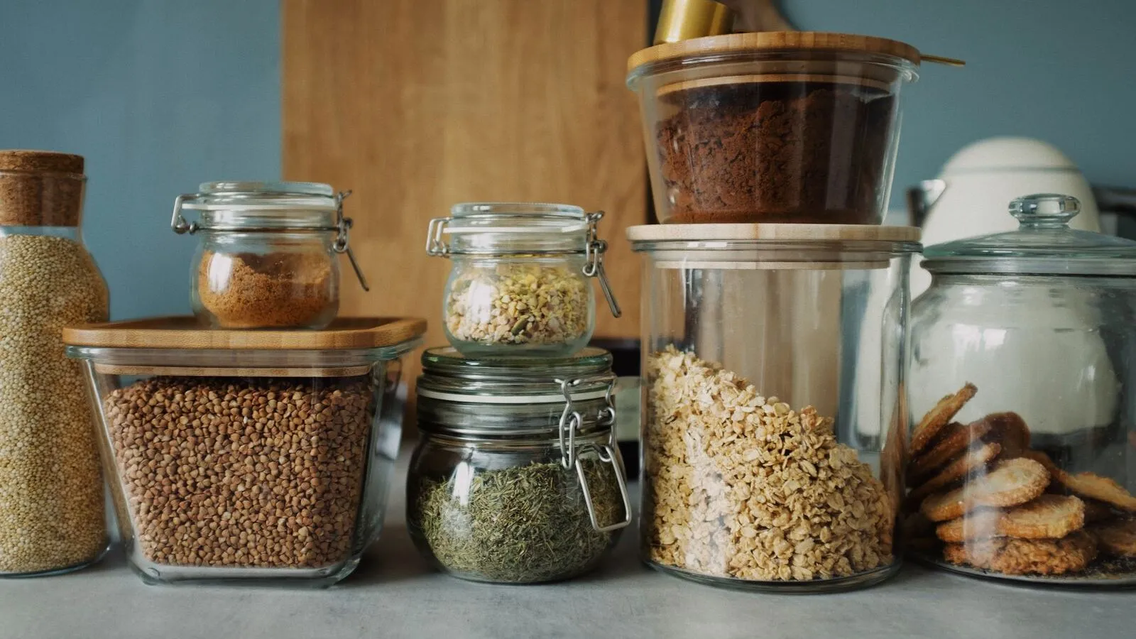 Glass jars of grains, dry goods, and cookies line a pantry counter.
