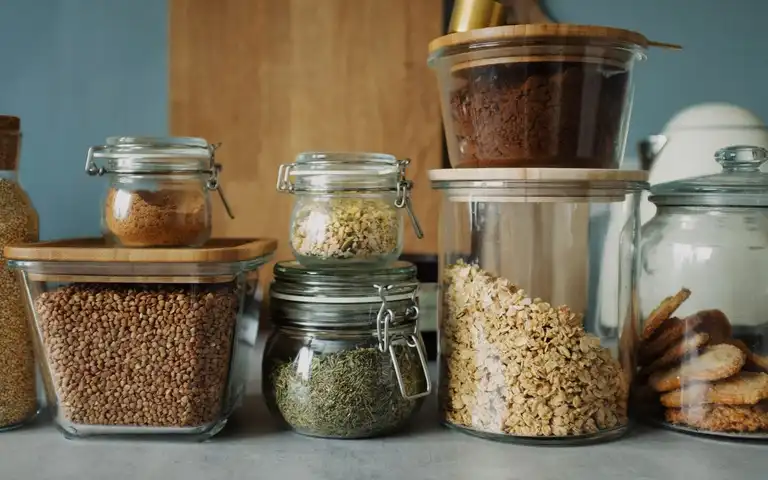 Glass jars of grains, dry goods, and cookies line a pantry counter.