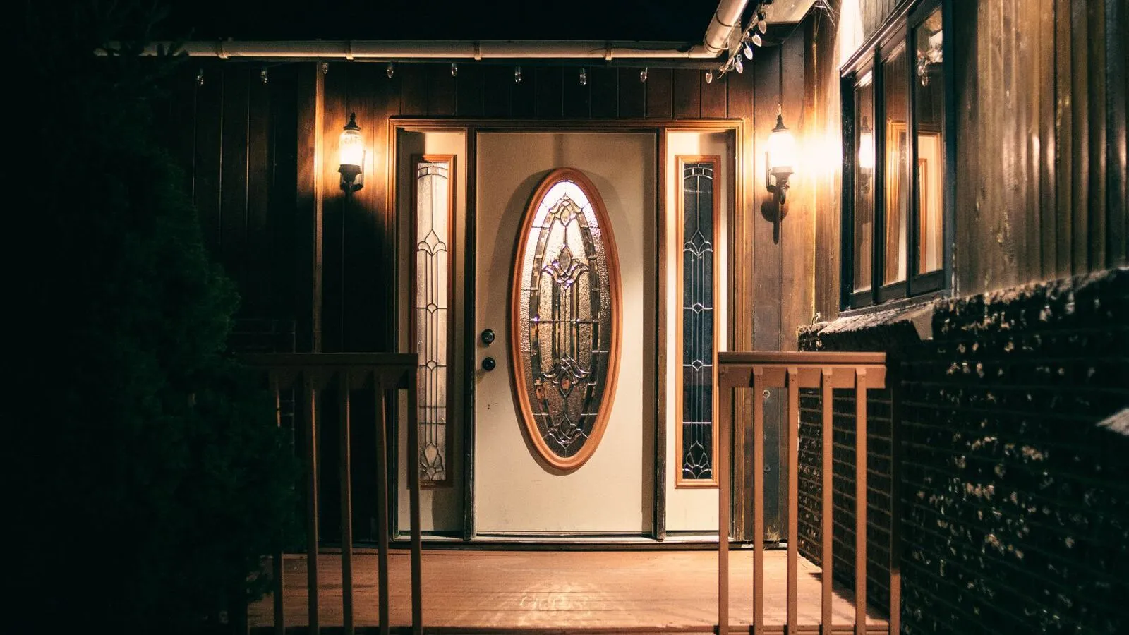 A house entrance and porch are lit at night.