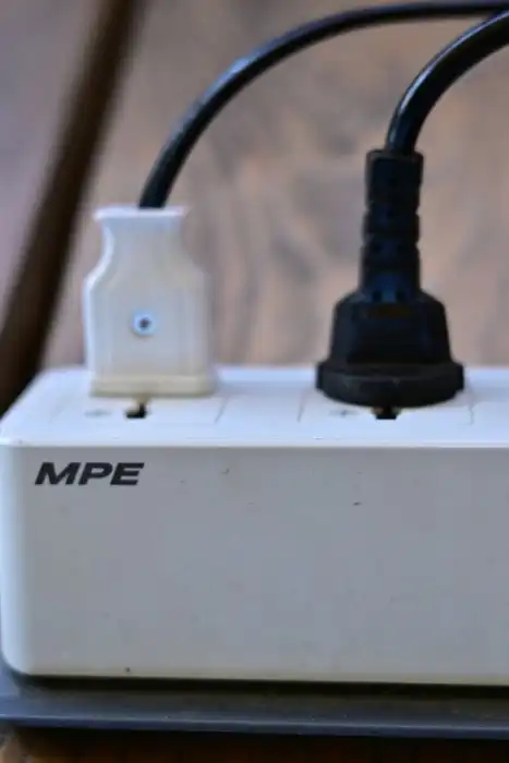 Power strip with two connected plugs and three USB ports on a wooden surface.