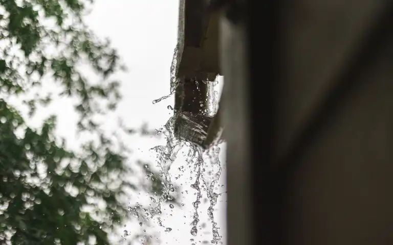 Rainwater spilling from a roof gutter during rainfall