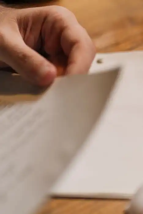 A hand resting on a printed document beside a glass of water.