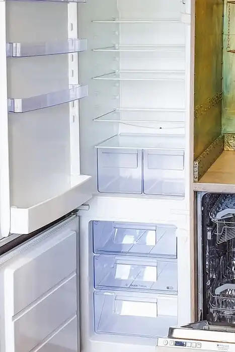 Open refrigerator and dishwasher beside a kitchen sink.