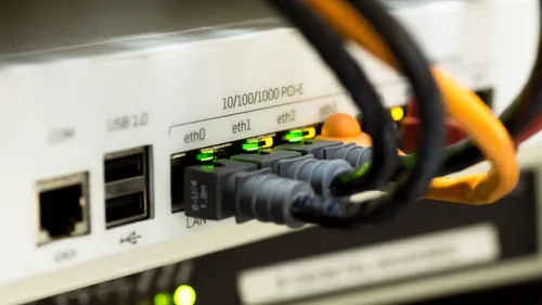 Ethernet cables plugged into LAN ports on a network device, with status lights illuminated.