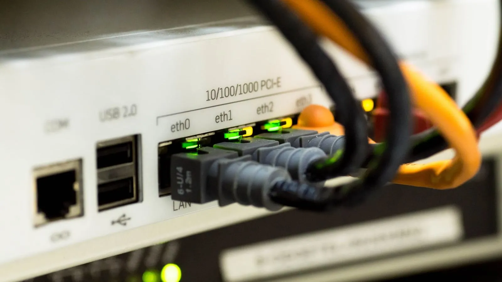Ethernet cables plugged into LAN ports on a network device, with status lights illuminated.