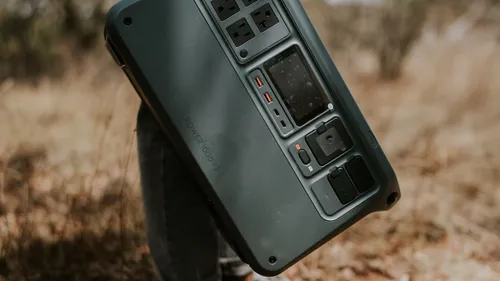 Close view of a portable power station with AC and USB outlets resting on an outdoor surface.