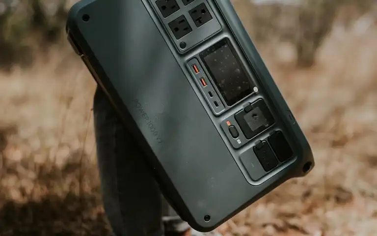 Close view of a portable power station with AC and USB outlets resting on an outdoor surface.