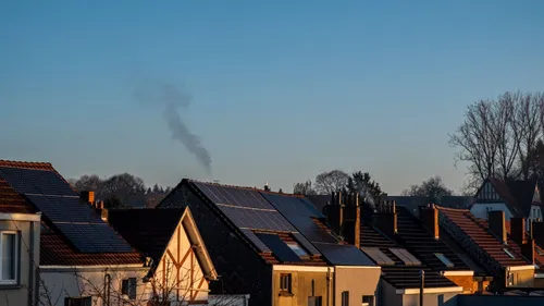 Solar panels on the roofs of neighboring houses under a clear sky.
