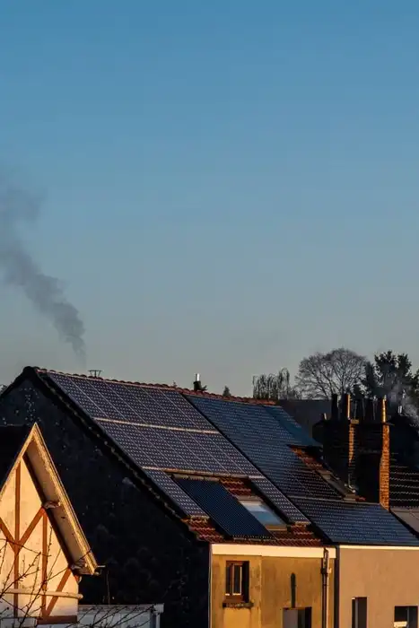 Solar panels on the roofs of neighboring houses under a clear sky.