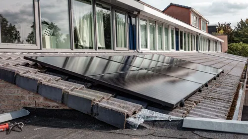 Rows of rooftop solar panels beside a long line of windows.
