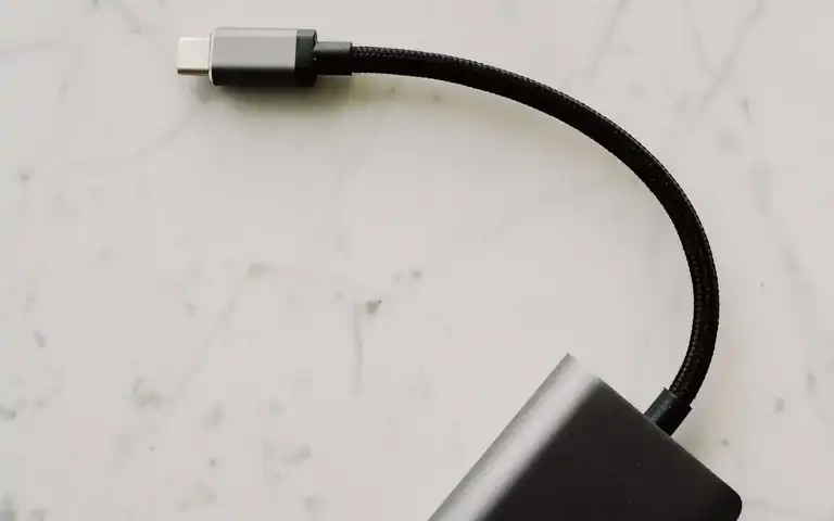 A short braided USB-C cable attached to an adapter on a white surface.