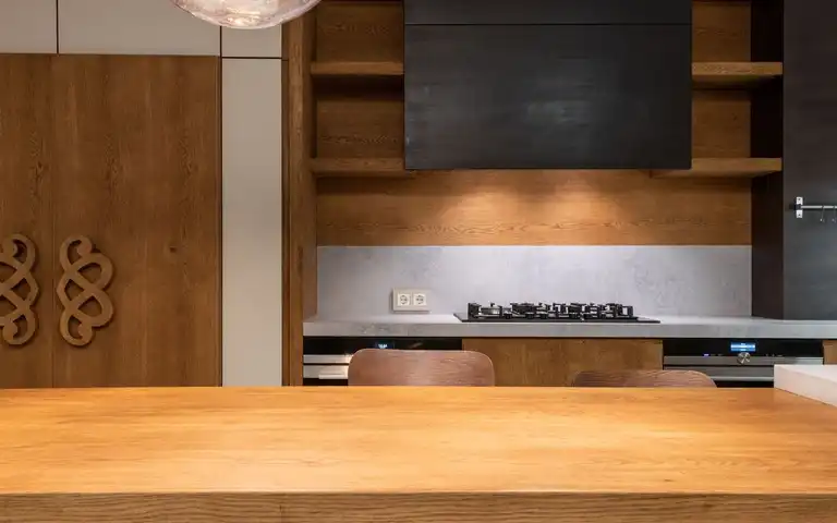 A modern kitchen with a gas cooktop is seen beyond a wooden counter.