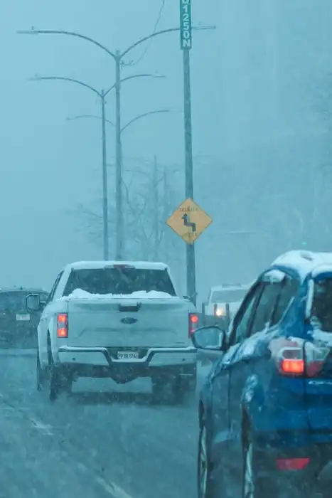 Cars traveling on a snow-covered urban street.