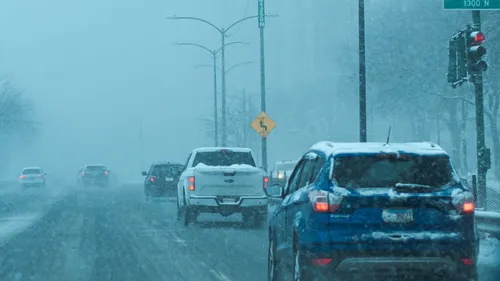 Cars traveling on a snow-covered urban street.